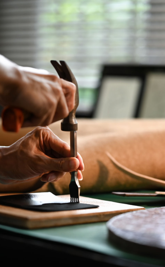Person crafting leather with hand tools.