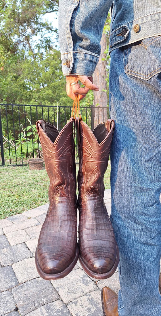 Person holding brown cowboy boots outside.