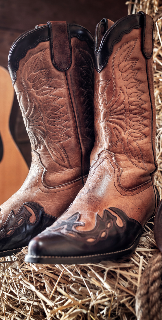 Brown leather cowboy boots on haystack.
